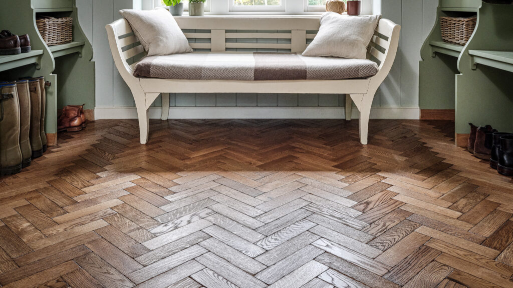 Warm oak herringbone parquet flooring, used in a boot room.
