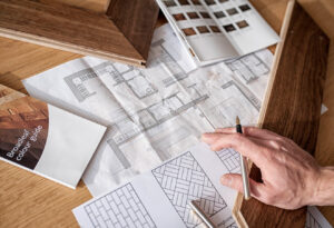 A designer goes over a building layout with wood samples, designs and colours on hand for inspiration.