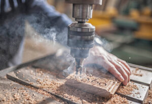 A carpenter drills holes into a piece of wood.
