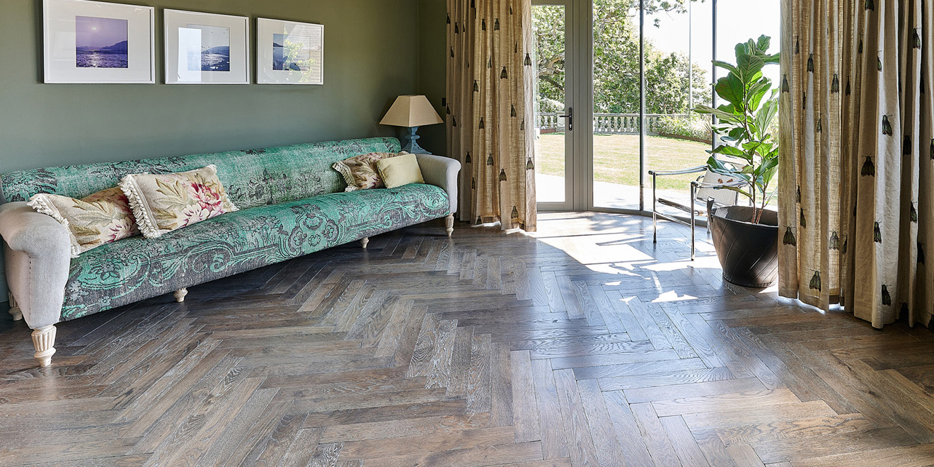Large oak parquet flooring laid in herringbone pattern in a North-facing room with turquoise sofa.