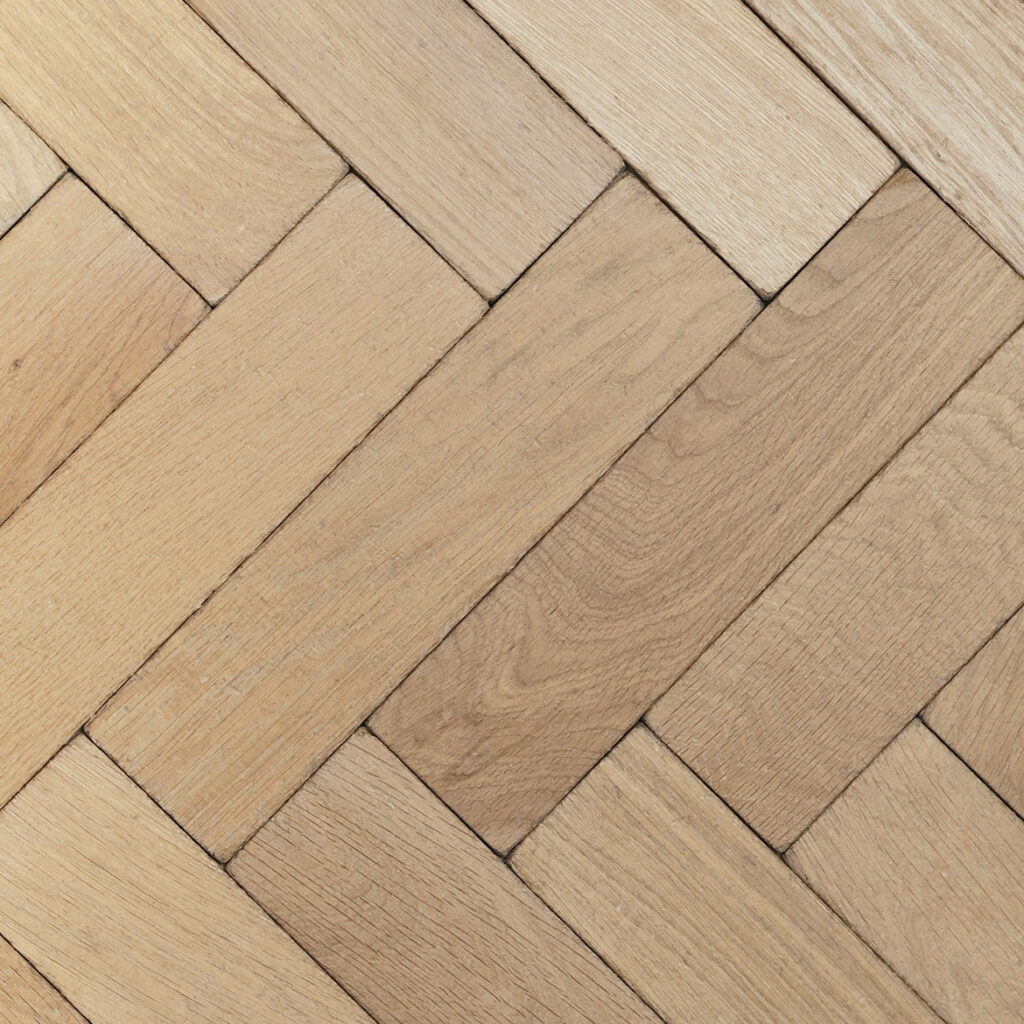 Natural solid oak parquet flooring laid in herringbone pattern.