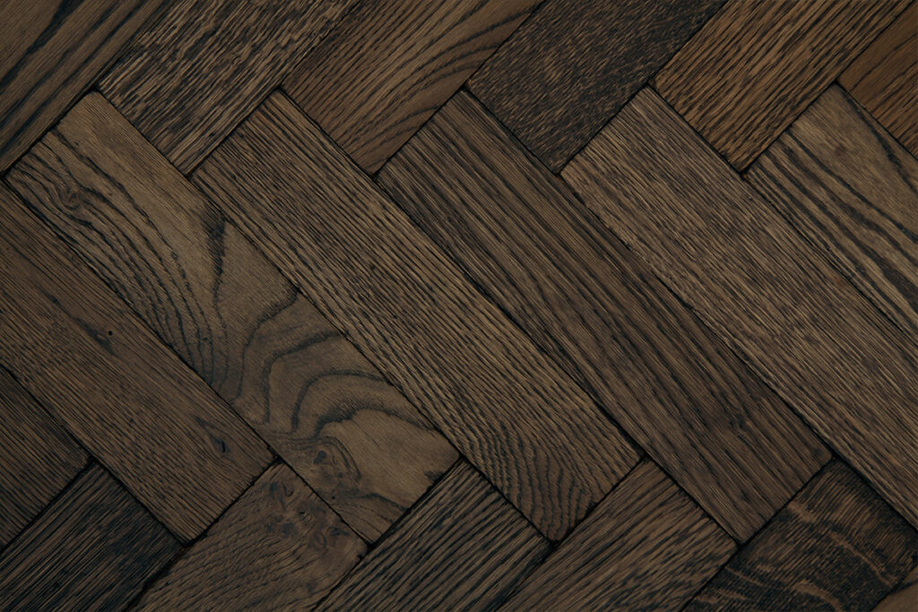 Dark oak vintage parquet flooring with visible grain and colour variation laid in herringbone pattern.