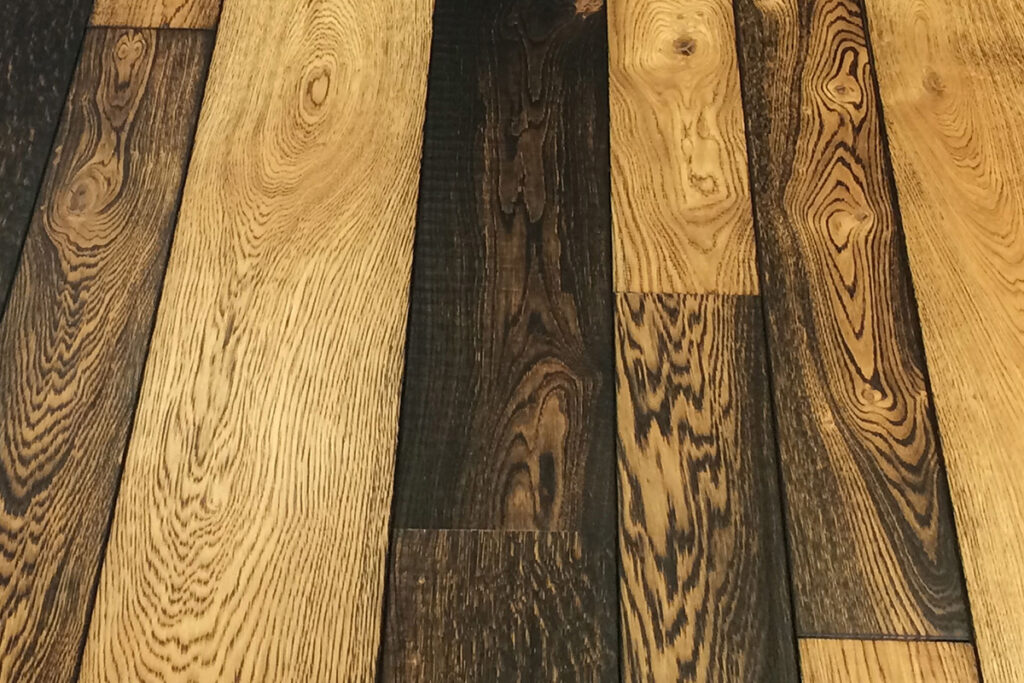 Mixed width floorboards with a mixed degree of burning across their face.